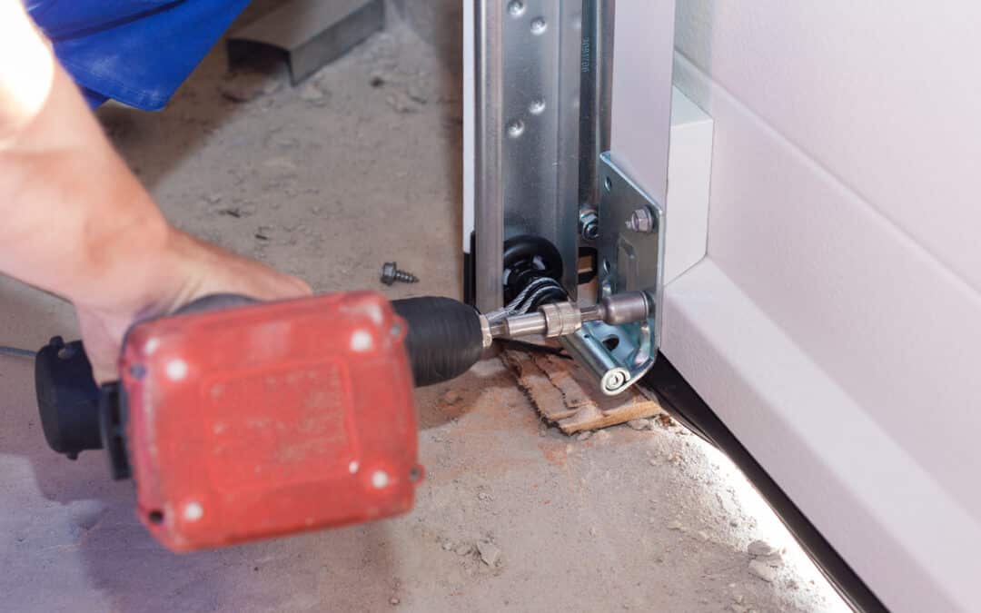 emergency garage door repair. Cropped view of professional worker install metal rail on garage door system in new house under construction, using electric screwdriver