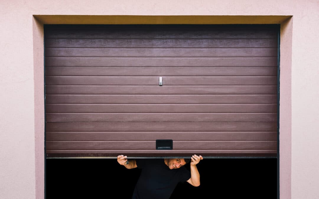 man holds garage door up halfway, broken garage door repair