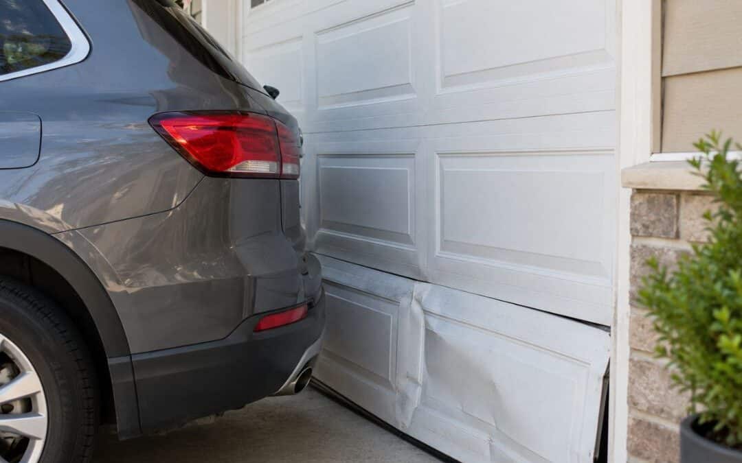 SUV backed into a residential garage door, causing visible damage to the lower panels