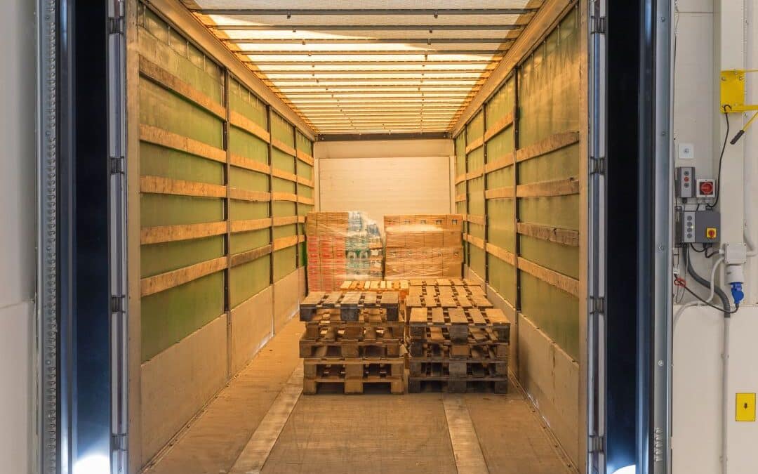 Commercial loading dock with a dock leveler extending into a delivery truck containing stacked wooden pallets.